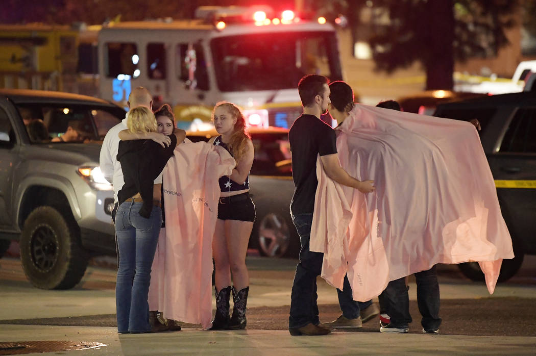 People comfort each other as they stand near the scene Thursday, Nov. 8, 2018, in Thousand Oaks, Calif. where a gunman opened fire Wednesday inside a country dance bar crowded with hundreds of peo ...