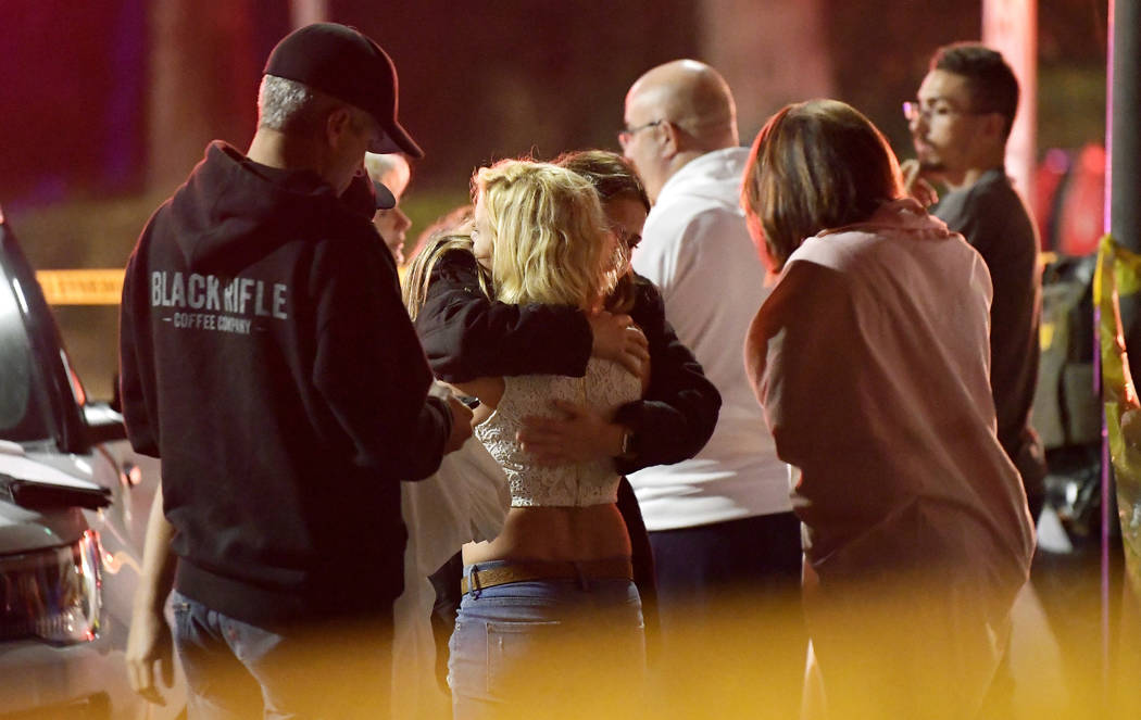 People comfort each other as they stand near the scene Thursday, Nov. 8, 2018, in Thousand Oaks, Calif., where a gunman opened fire Wednesday inside a country dance bar crowded with hundreds of pe ...