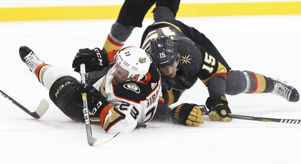 Anaheim Ducks center Brian Gibbons (23) and Golden Knights defenseman Jon Merrill (15) fall to the ice while battling for the puck during the second period of an NHL hockey game at T-Mobile Arena ...
