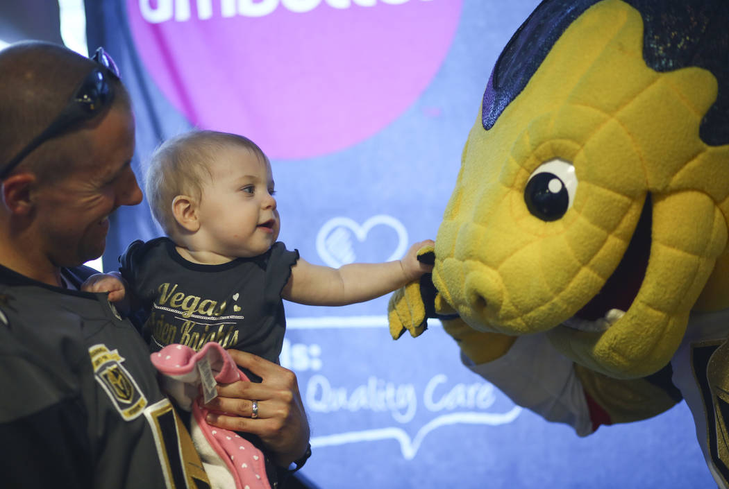 Steven Garrett holds his daughter Aurora as she greets Golden Knights mascot Chance during the second annual "Silver and Gold" food drive at City National Arena in Las Vegas on Thursday, ...