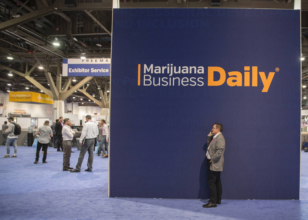 Jaques Santucci, right, with Strimo LP, takes a call in front of signage for the Marijuana Business Daily during the MJBizCon on Wednesday, November 14, 2018, at the Las Vegas Convention Center, i ...