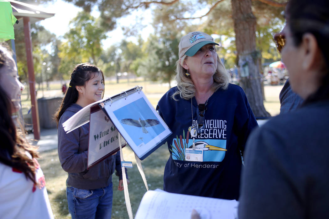 Jane Taylor shows the Herrera family that Rupert Herrera's arm span would be an Osprey at a booth at Migratory Bird Day at Sunset Park in Las Vegas, Sunday, Nov. 18, 2018. Different organizations ...