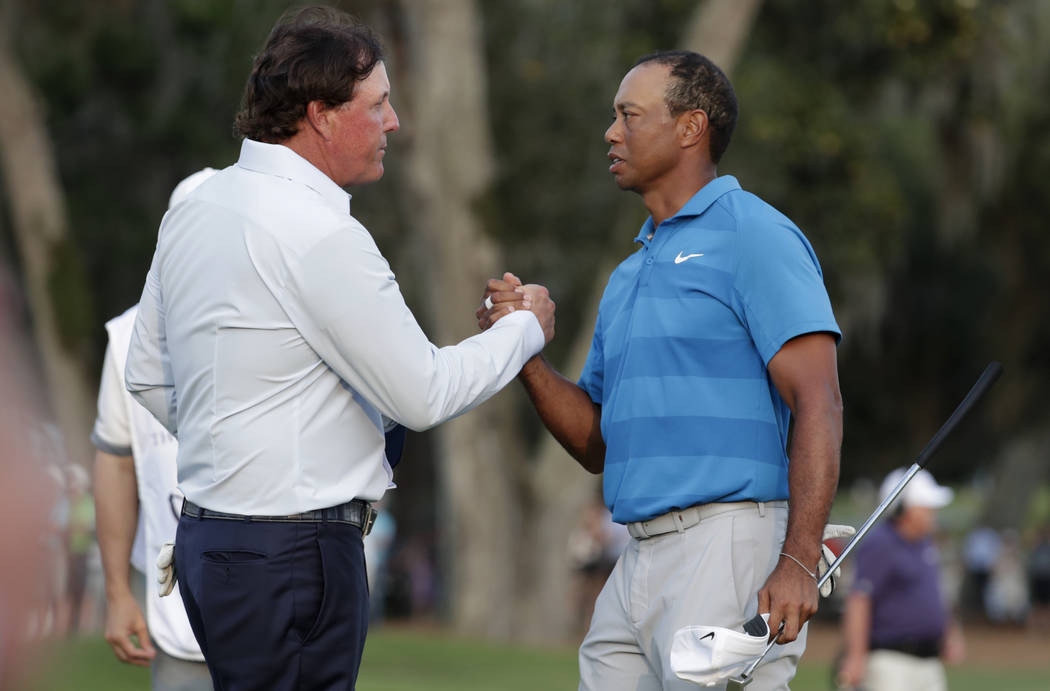 In this May 10, 2018, file photo, Phil Mickelson, left, and Tiger Woods shake hands after the first round of the Players Championship golf tournament, in Ponte Vedra Beach, Fla. (AP Photo/Lynne Sl ...