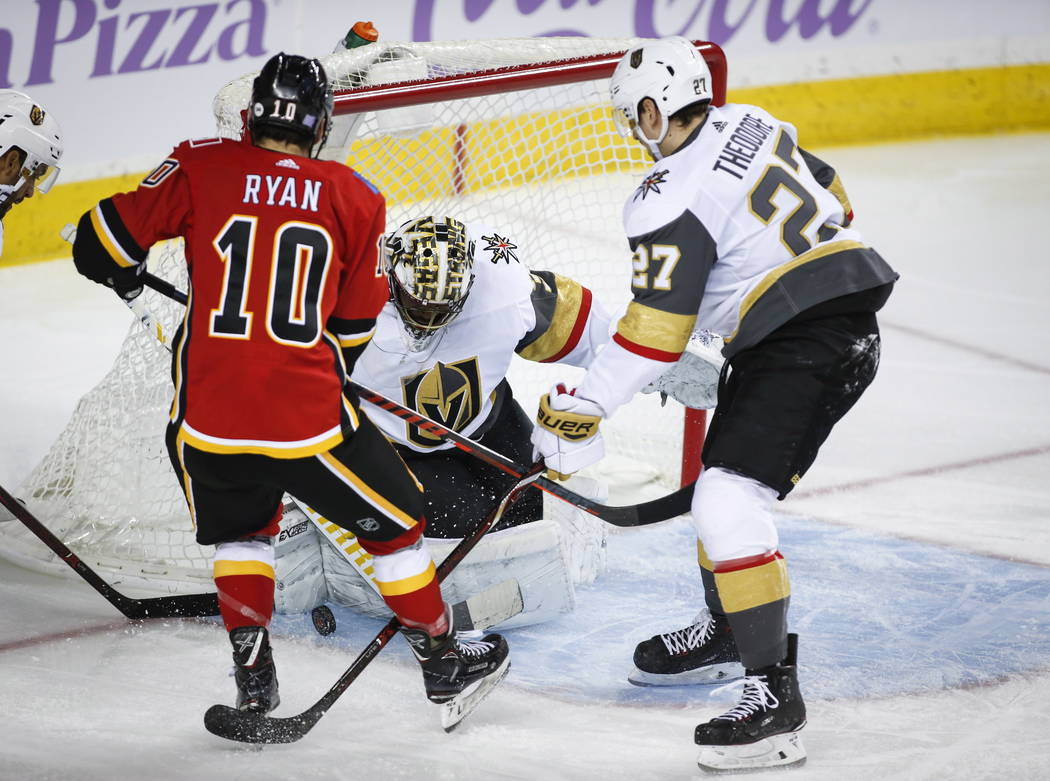 Vegas Golden Knights goalie Malcolm Subban, center, stops a shot from Calgary Flames' Derek Ryan, left, as Golden Knights' Shea Theodore looks on during first-period NHL hockey game action in Cal ...