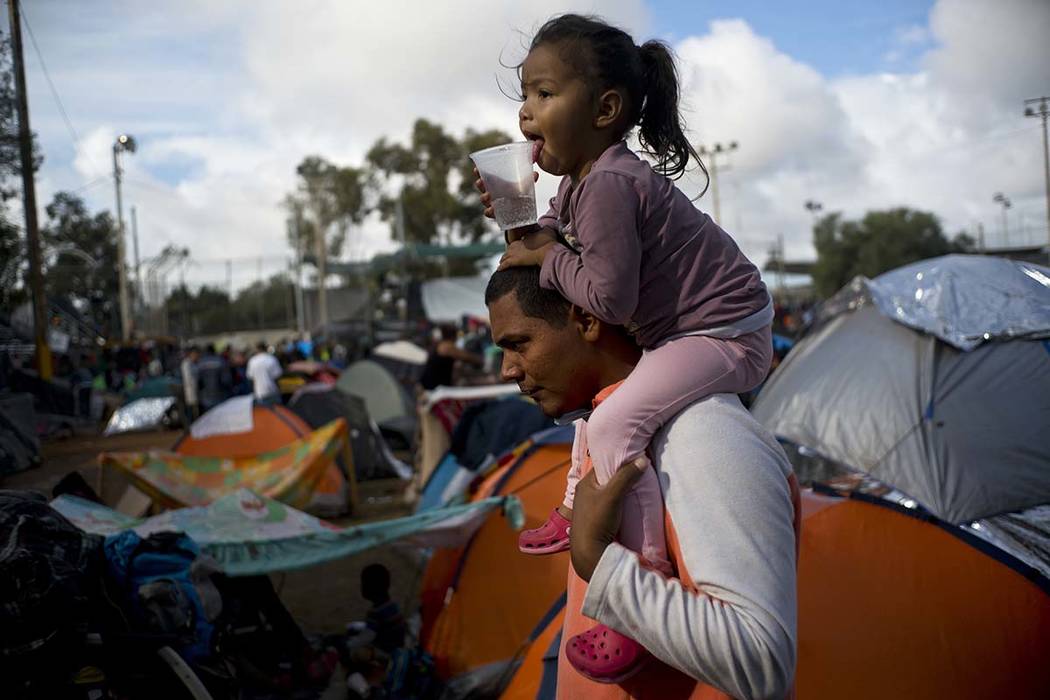 A man carries a girl on his shoulders at a migrant shelter in Tijuana, Mexico, Thursday, Nov. 22, 2018. Several thousand Central American migrants arrived in Tijuana last week more than a month af ...