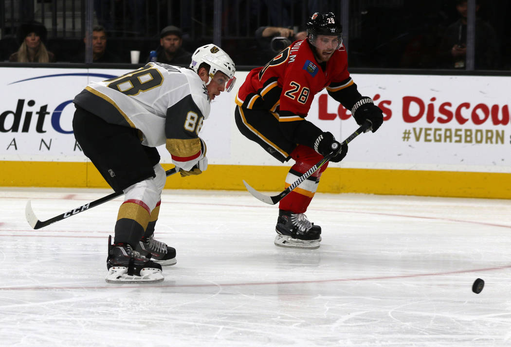 Vegas Golden Knights defenseman Nate Schmidt (88) and Calgary Flames center Elias Lindholm (28) go after the puck during the second period of an NHL game in Las Vegas, Friday, Nov. 23, 2018. Heidi ...