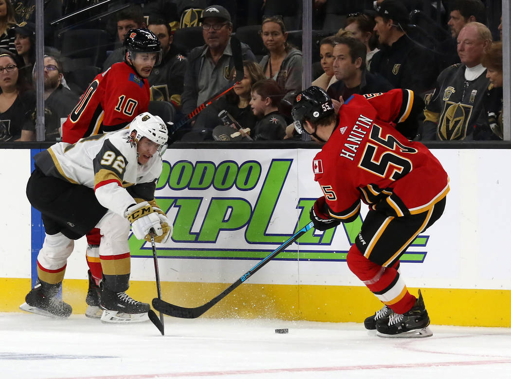Vegas Golden Knights left wing Tomas Nosek (92) shoots the puck past Calgary Flames defenseman Noah Hanifin (55) as center Derek Ryan (10) defends during the first period of an NHL game in Las Veg ...
