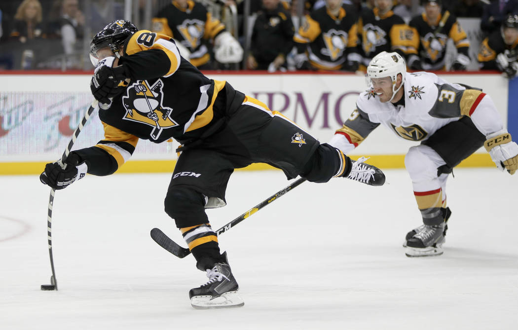 Pittsburgh Penguins' Phil Kessel, left, snaps a shot as Vegas Golden Knights' Colin Miller (6) defends during the second period of an NHL hockey game Thursday, Oct. 11, 2018, in Pittsburgh. Kessel ...