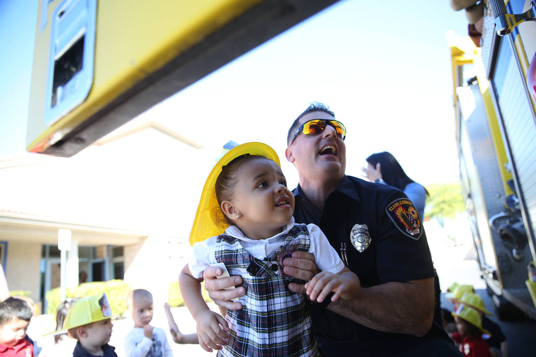Clark County Fire Department Firefighter Adam Smith carries Giovanna McMurry, 3, into a fire engine during a fire awareness visit to Merryhill Preschool, 5055 S. Durango Dr., in Las Vegas, Wednesd ...
