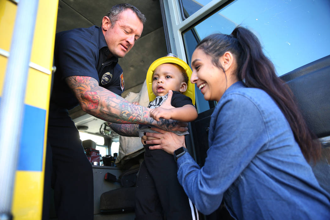 Clark County Fire Department firefighter Jonathan McBreen, left, after showing Avery Duncan, 1, inside a fire engine with infant co-lead Felecia Esparza, during a fire awareness visit to Merryhill ...