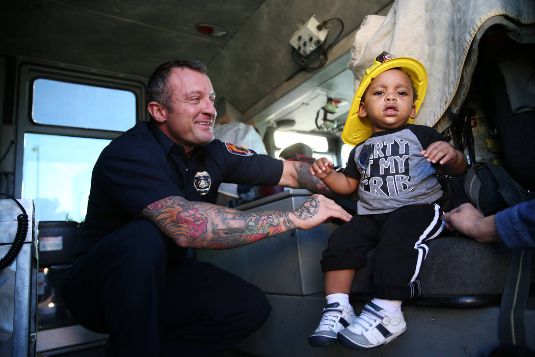 Clark County Fire Department firefighter Jonathan McBreen, left, shows Avery Duncan, 1, inside a fire engine during a fire awareness visit to Merryhill Preschool, 5055 S. Durango Dr., in Las Vegas ...
