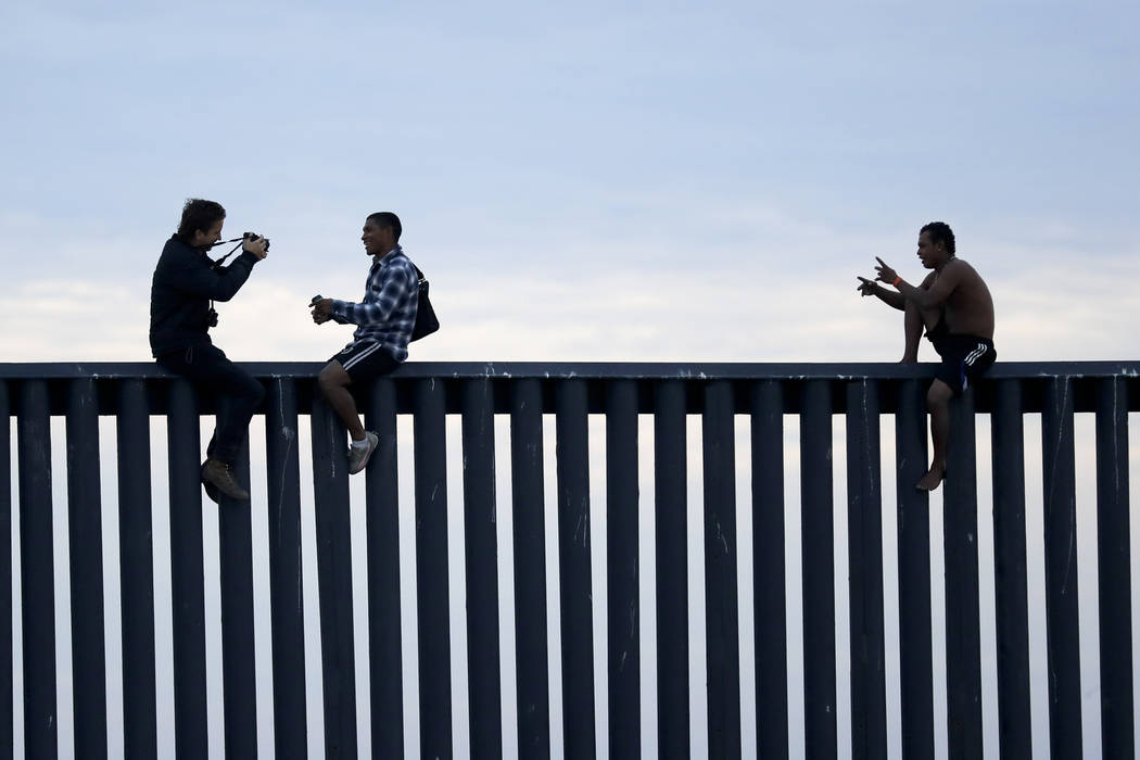 Two Honduran men pose as a photographer, at left, takes their picture after the group climbed the border wall separating Tijuana, Mexico, and San Diego, before climbing back down on the Mexican si ...
