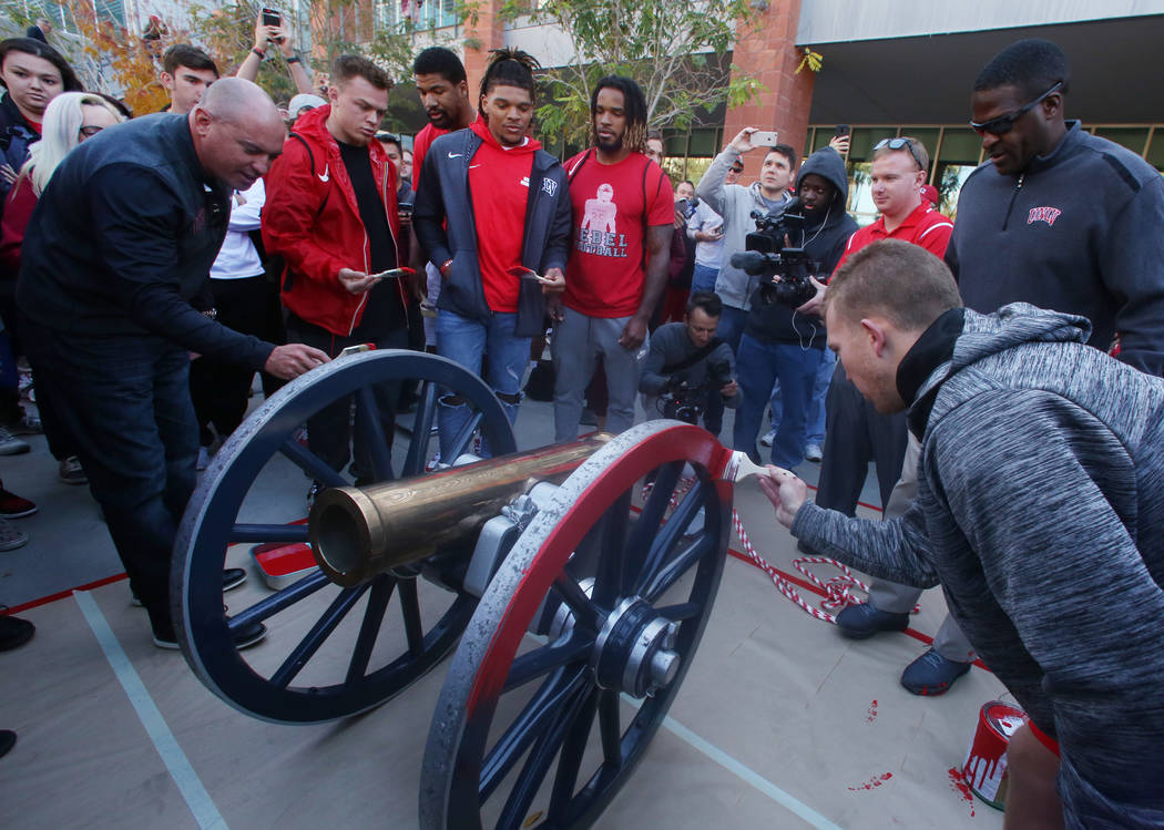 UNLV students and officials watch as Rebels football players, including kicker Evan Pantels, right, and head coach Tony Sanchez, far left, brush red paint on the Fremont Cannon outside of the Stud ...