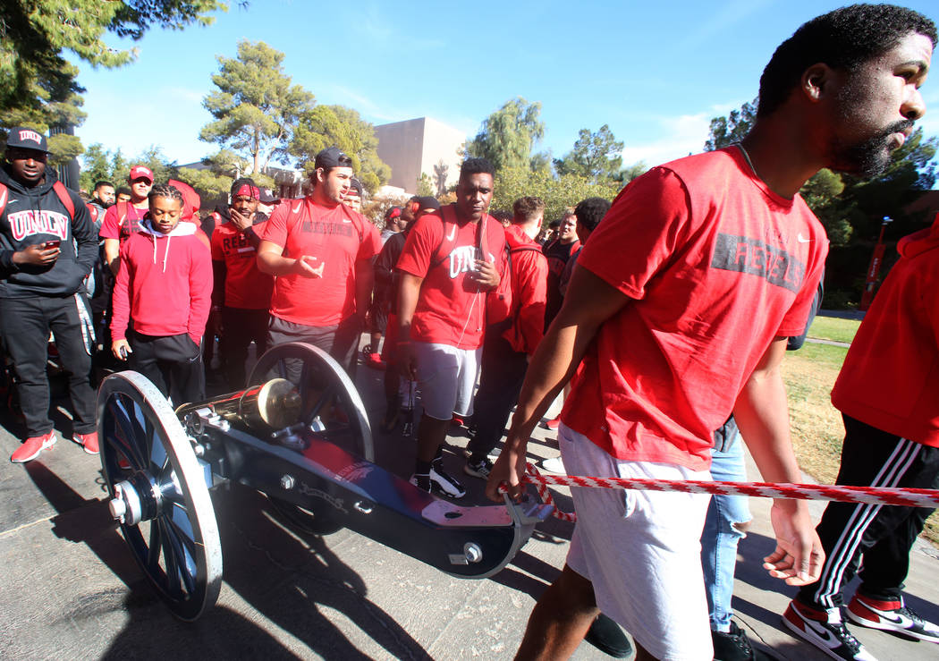 UNLV football players, including quarterback Armani Rogers, front, pull the Fremont Cannon to be painted red outside of the Student Union at UNLV on Monday, Nov, 26, 2019, in celebration of their ...