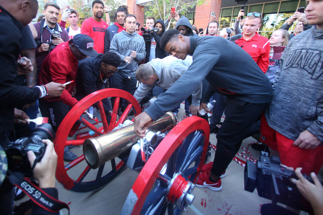 UNLV students and officials watch as Rebels football players, including linebacker Javin White, right, brush red paint on the Fremont Cannon outside of the Student Union at UNLV on Monday, Nov, 26 ...