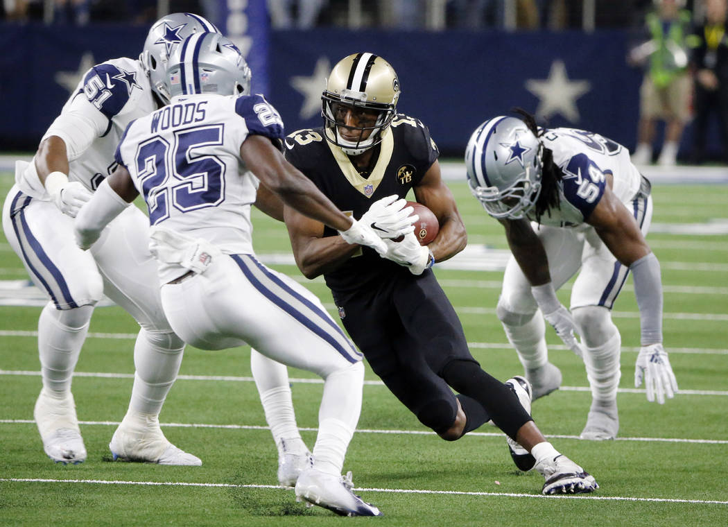 New Orleans Saints wide receiver Michael Thomas (13) makes a catch in front of Dallas Cowboys free safety Xavier Woods (25) during the second half of an NFL football game, in Arlington, Texas, Thu ...