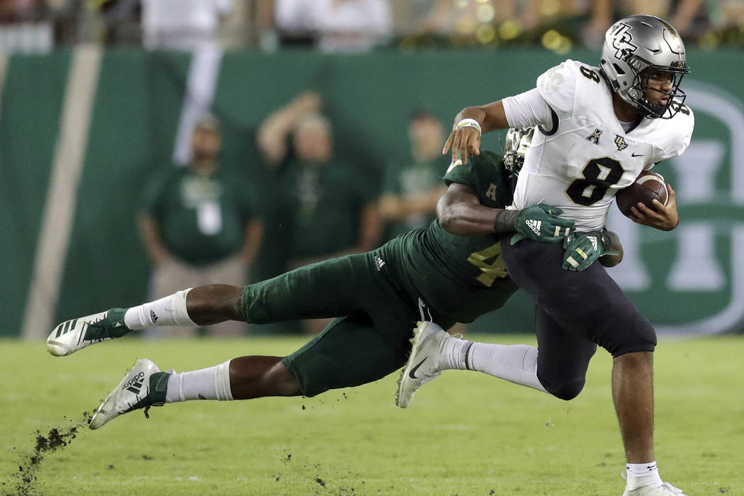 Central Florida's Darriel Mack Jr., right, fights off a tackle from South Florida's Greg Reaves during the second half of an NCAA college football game Friday, Nov. 23, 2018, in Tampa, Fla. (AP Ph ...