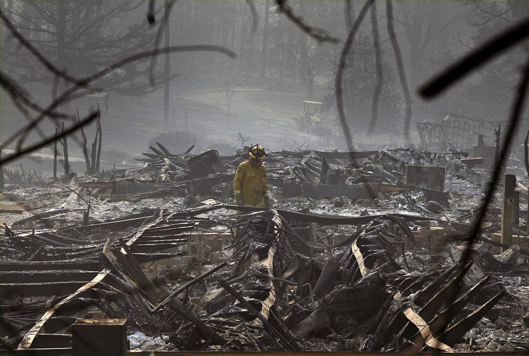 A firefighter searches for human remains in a trailer park destroyed in the Camp Fire, in Paradise, Calif., on Nov, 16, 2018. (AP Photo/John Locher)