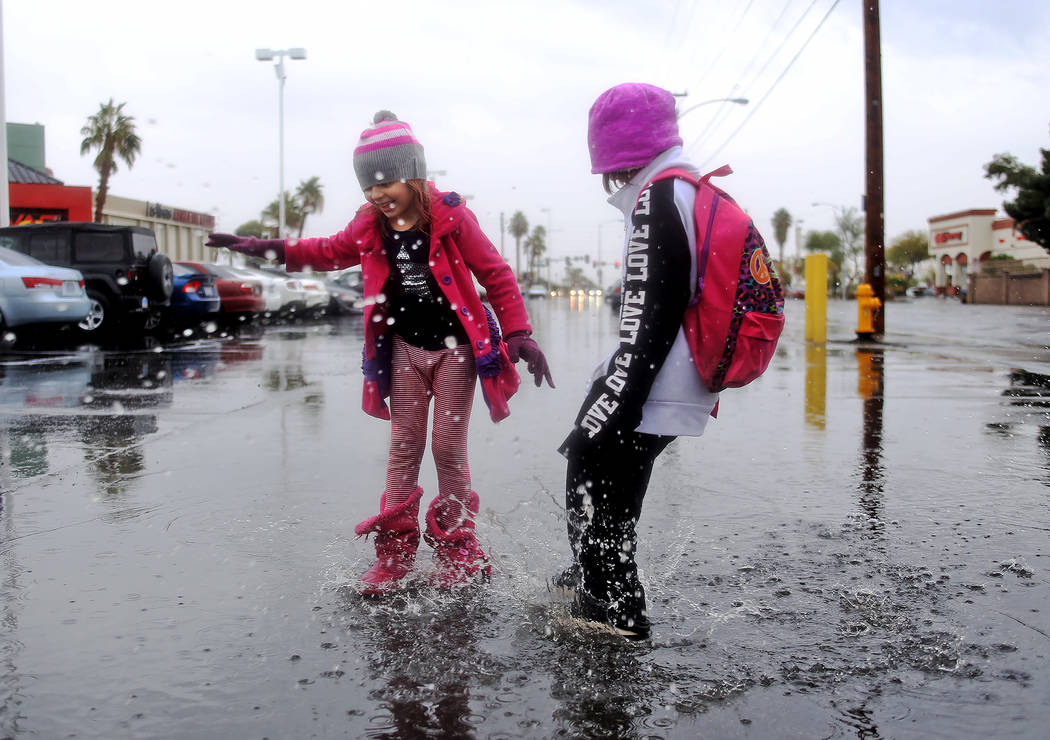 Violette Frankenberg, 6, left, jumps in rain puddles with her sister Scarlette Frankenberg, 8, right, in the parking lot of the Las Vegas Athletic Club in Las Vegas, Thursday, Nov. 29, 2018. Rache ...