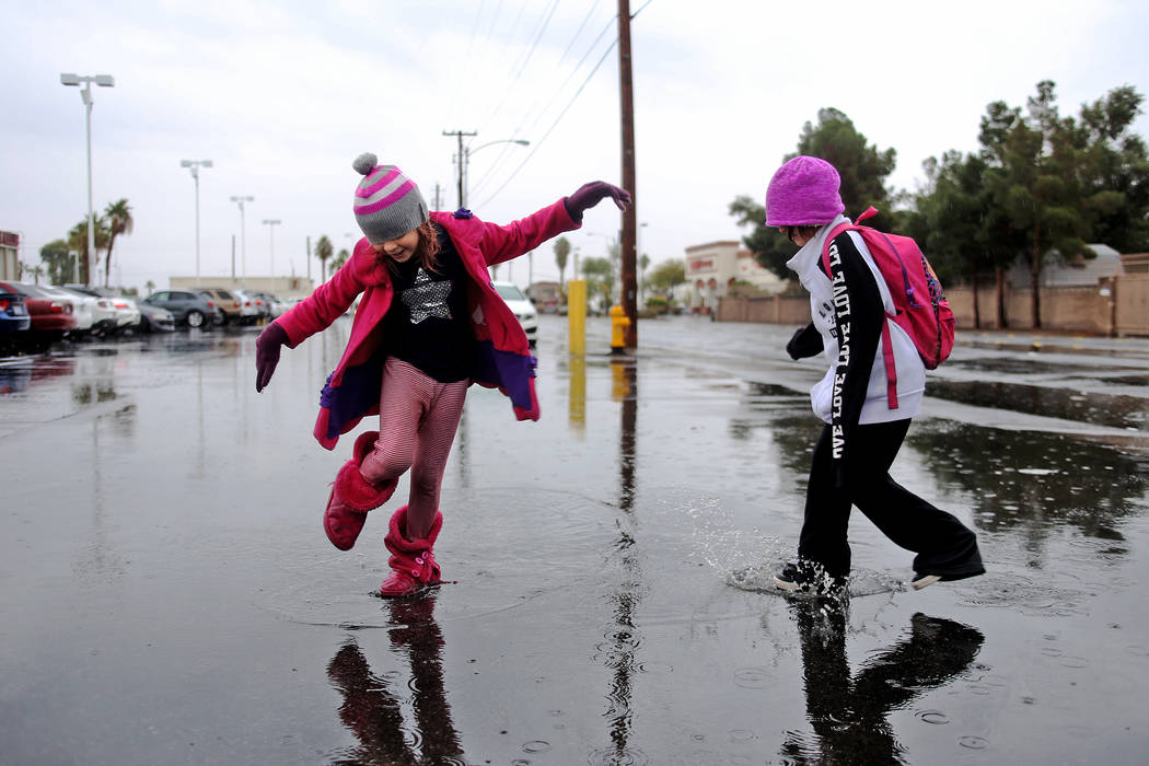 Violette Frankenberg, 6, left, jumps in rain puddles with her sister Scarlette Frankenberg, 8, right, in the parking lot of the Las Vegas Athletic Club in Las Vegas, Thursday, Nov. 29, 2018. Rache ...