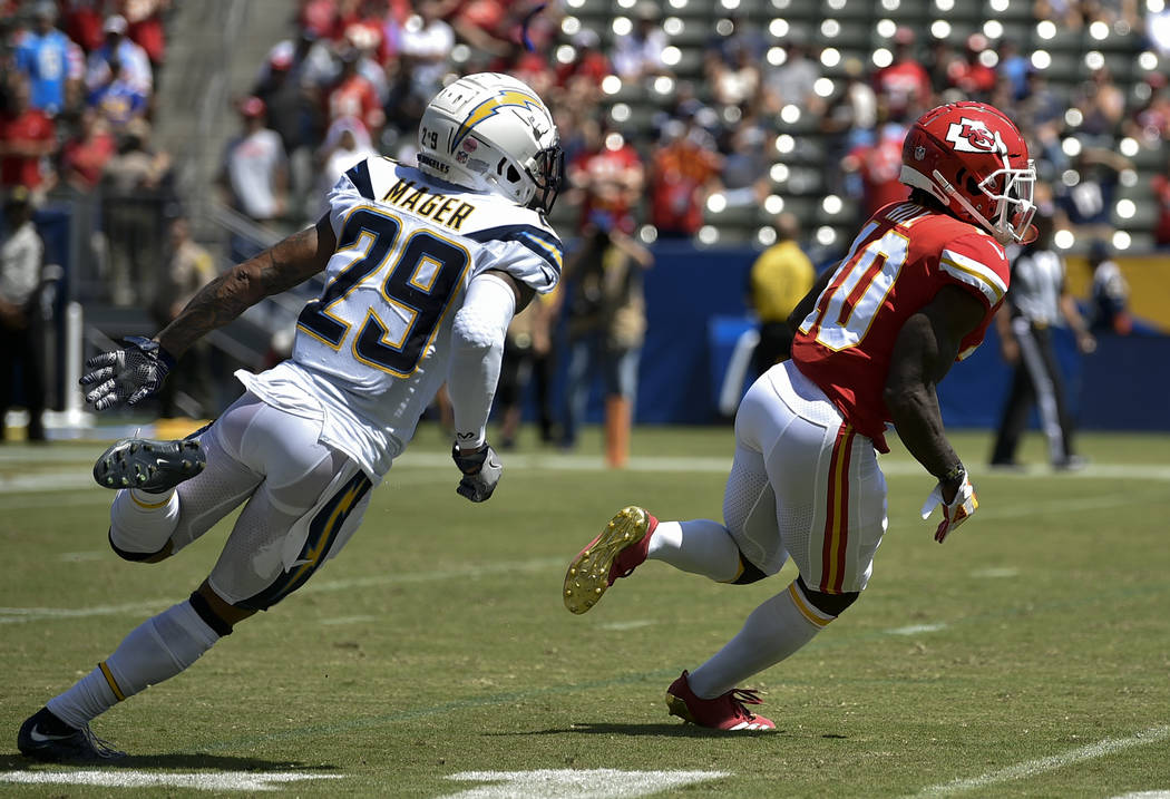 Kansas City Chiefs wide receiver Tyreek Hill, right, runs back a punt return defended by Los Angeles Chargers cornerback Craig Mager during the first half of an NFL football game in Carson, Calif. ...