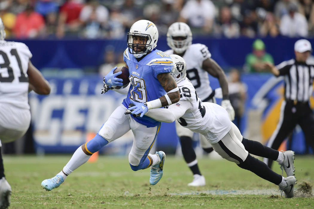 Los Angeles Chargers wide receiver Keenan Allen carries as Oakland Raiders defensive back Leon Hall hauls him down during the second half of an NFL football game Sunday, Oct. 7, 2018, in Carson, C ...