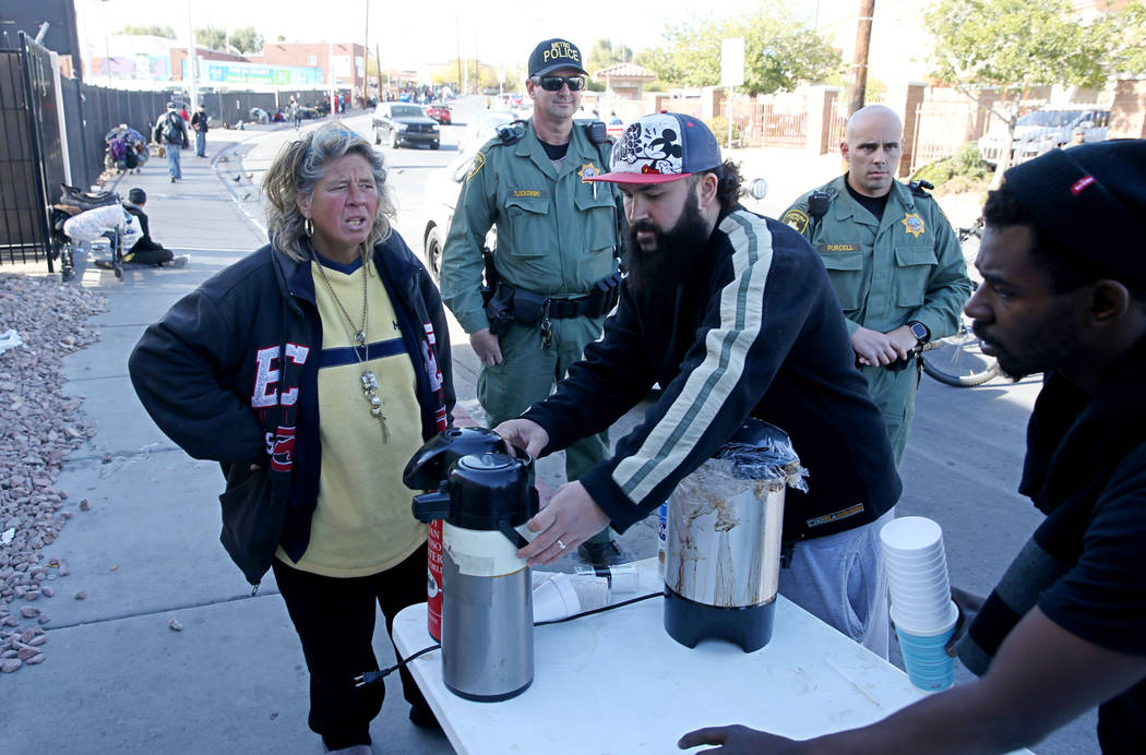 Las Vegas police watch as Joey Lankowski, center, cleans up the area where he was distributing food on Foremaster Lane near Las Vegas Boulevard Wednesday, Nov. 28, 2018. Lankowski was cited for pa ...