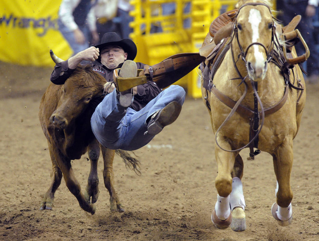 Steer wrestler Matt Reeves of Cross Plains, Texas wrestles a steer to a three way tie sixth place time of 4.30 seconds during the steer wrestling competition of the seventh go-round of the 54th Wr ...