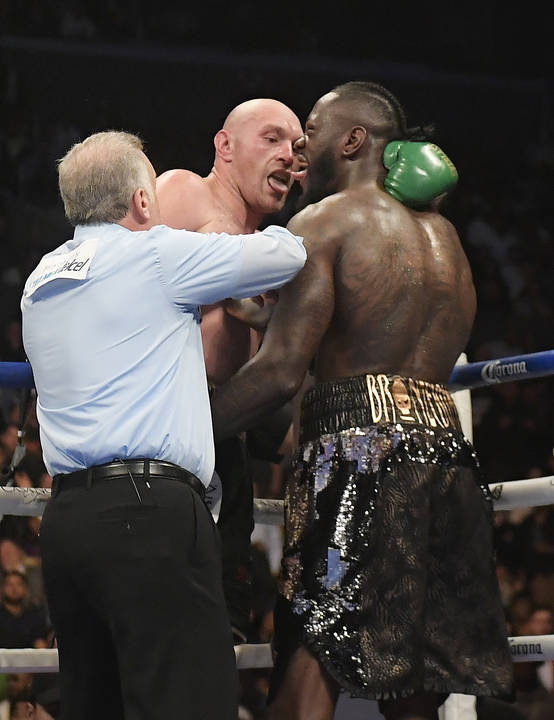 Tyson Fury, center of England, and Deontay Wilder, right, taunt each other as referee Jack Reiss gets between them during a WBC heavyweight championship boxing match, Saturday, Dec. 1, 2018, in Lo ...