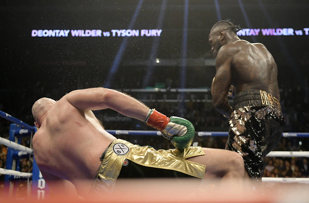 Deontay Wilder, right, knocks down Tyson Fury, of England, during the 12th round of a WBC heavyweight championship boxing match, Saturday, Dec. 1, 2018, in Los Angeles. (AP Photo/Mark J. Terrill)
