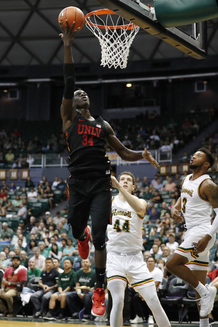 UNLV forward Cheikh Mbacke Diong (34) goes for the basket over Hawaii center Dawson Carper (44) and guard Eddie Stansberry (3) during the first half of an NCAA college basketball game at the Diamo ...