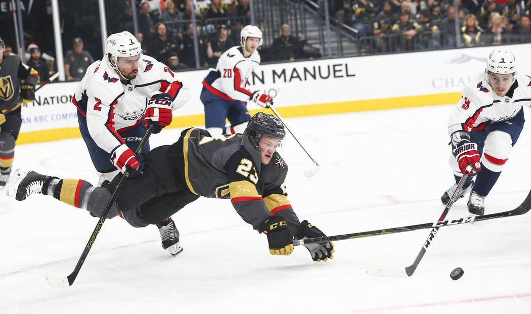 Golden Knights left wing Daniel Carr (23) gets pushed to the ice by Washington Capitals defenseman Matt Niskanen (2) while battling for the puck against Washington Capitals defenseman Dmitry Orlov ...