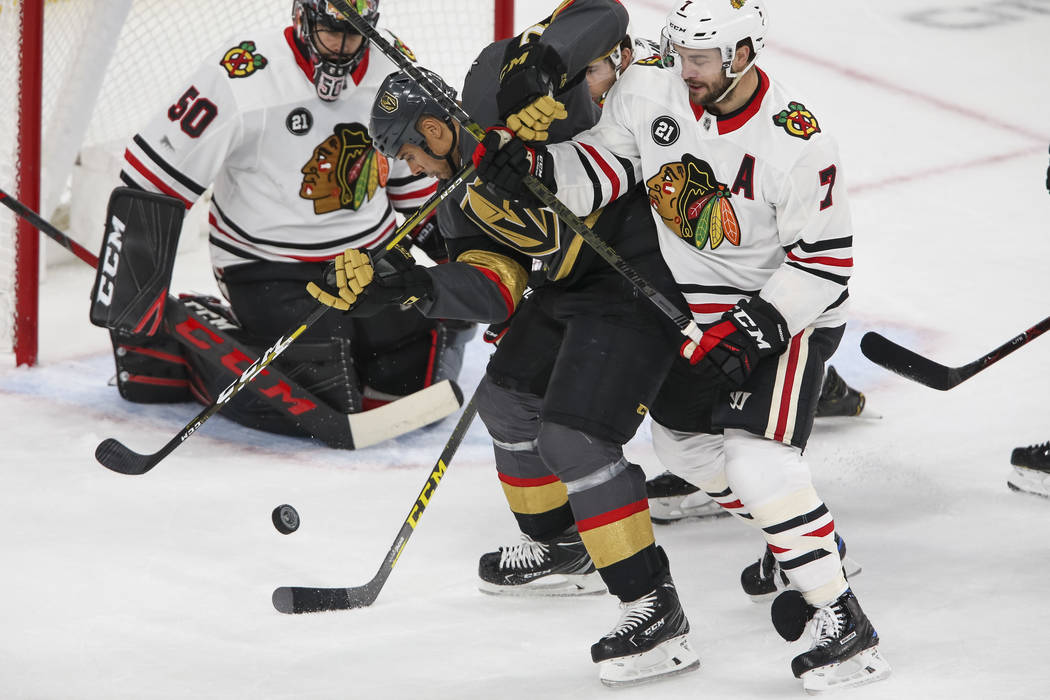 Vegas Golden Knights right wing Ryan Reaves (75) and Chicago Blackhawks defenseman Brent Seabrook (7) vie for the puck in front of Blackhawks goaltender Corey Crawford (50) during the first period ...