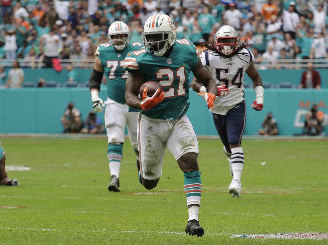 Miami Dolphins running back Frank Gore (21) runs the ball, during the first half of an NFL football game against the New England Patriots, Sunday, Dec. 9, 2018, in Miami Gardens, Fla. (AP Photo/Ly ...