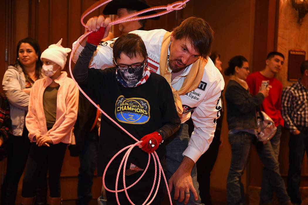 World champion steer wrestler Tyler Pearson gives a roping lesson to Gavin Kilcullen of Henderson, one of the children invited to the Golden Circle of Champions Banquet on Sunday at the South Poin ...