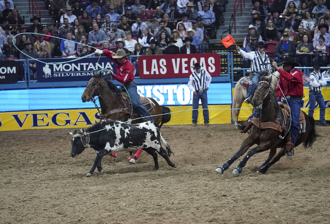 Trey Yates of Pueblo, Colo., left, and Aaron Tsinigine of Tuba City, Ariz. compete in the team roping event during the sixth go-round of the National Finals Rodeo at the Thomas & Mack Center i ...