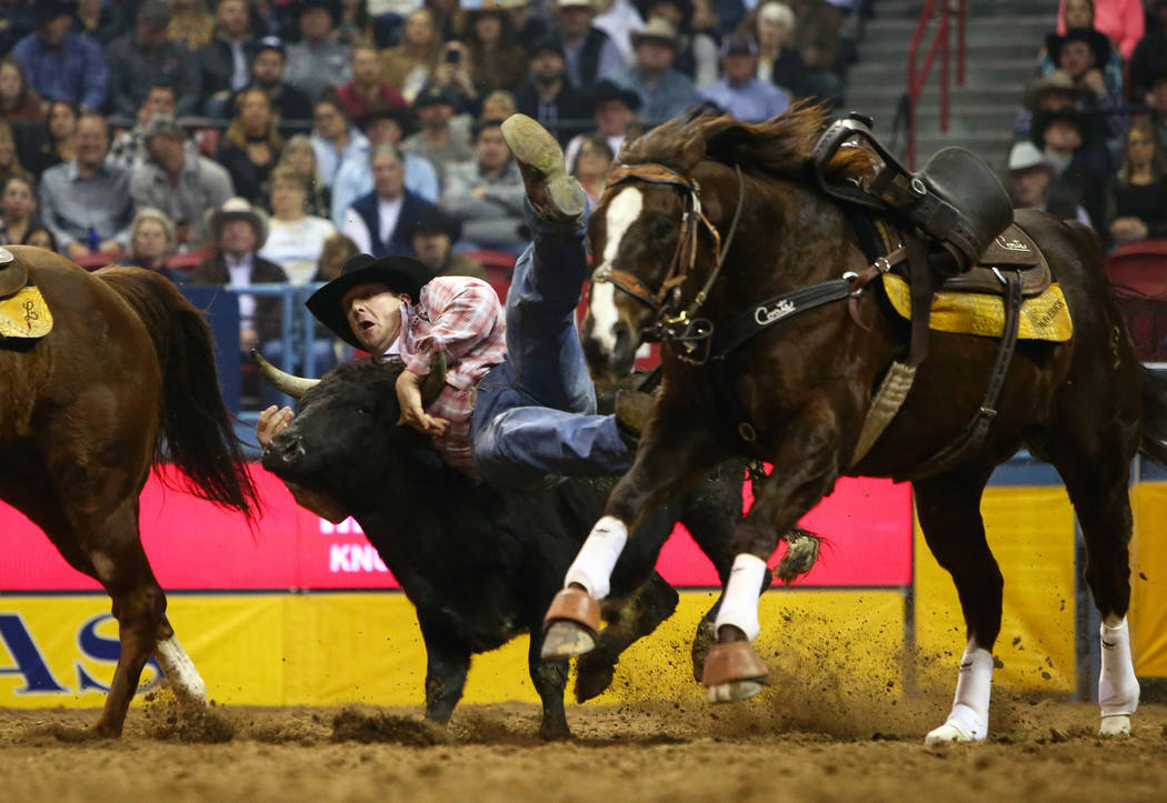 Nick Guy of Sparta, Wis. (104) jumps onto a steer while competing in steer wrestling during the sixth go-round of the National Finals Rodeo at the Thomas & Mack Center in Las Vegas, Tuesday, D ...