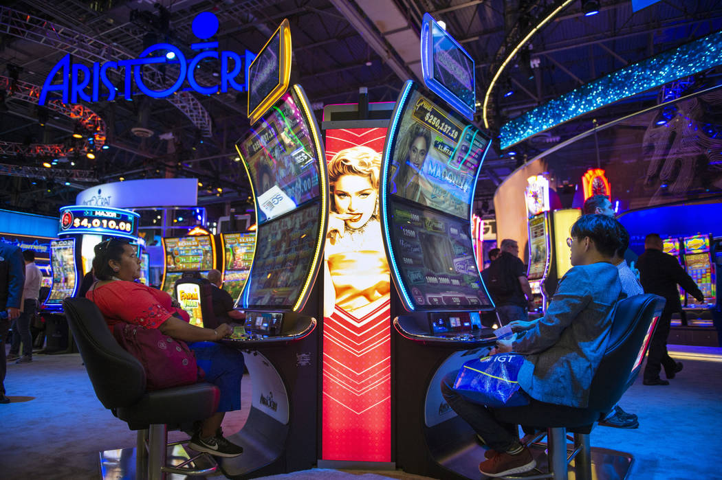 Attendees try out Madonna themed slot machines that feature a curved screen at the Aristocrat booth at the 18th annual Global Gaming Expo at Sands Expo and Convention Center in Las Vegas, Thursday ...