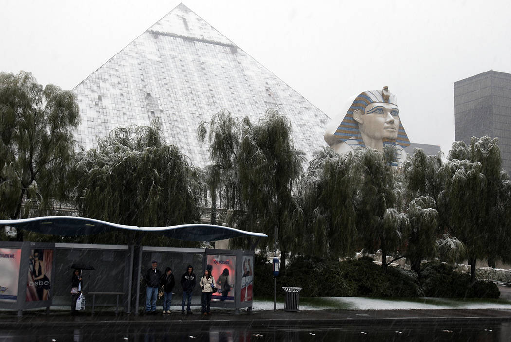 People wait for a bus as falling snow covers the Luxor on the Las Vegas Strip, Dec. 17, 2008. ( ...