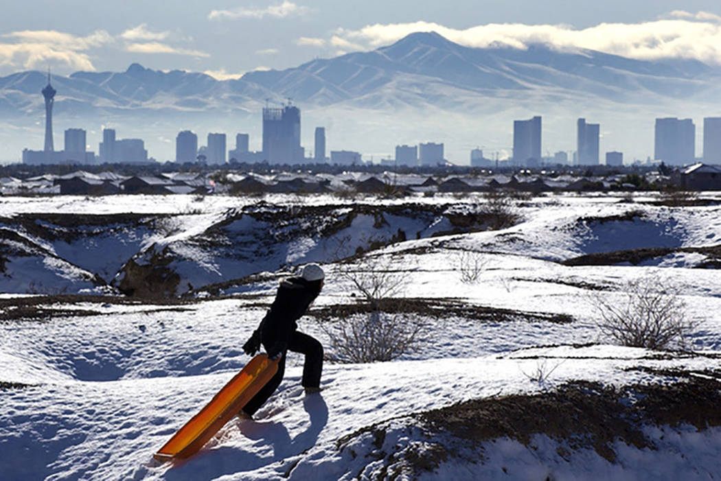 With the Las Vegas skyline looming in the background, Kymberlee Nguyen makes her way to the top of a hill while sledding in a desert region near North Durango Road on Dec. 18, 2008. (Las Vegas Rev ...