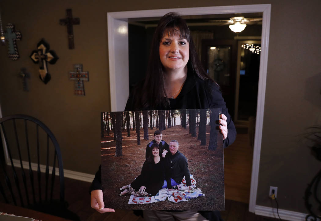 In this Thursday, Dec. 20, 2018 photo, Reagen Adair poses for a photo at her home holding a portrait of herself, with her husband Dale and son Mason, in Murchison, Texas. Adair, a fifth-grade teac ...