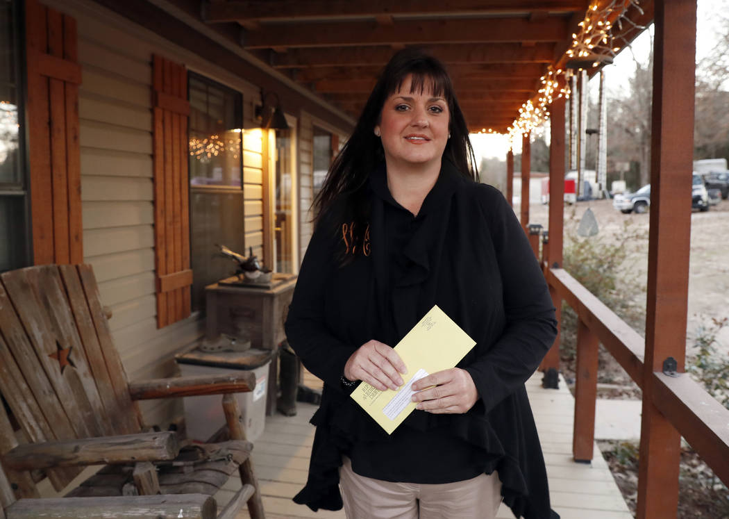 In this Thursday, Dec. 20, 2018 photo, Reagen Adair holds on to a RIP Medical Debt yellow envelope as she poses for a photo at her home in Murchison, Texas. The co-founders of RIP Medical Debt buy ...