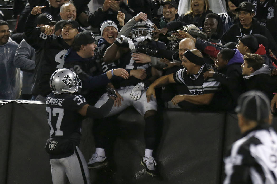Oakland Raiders' Dwayne Harris, center, celebrates with fans after returning a punt for a touchdown against the Denver Broncos during the first half of an NFL football game in Oakland, Calif., Mon ...