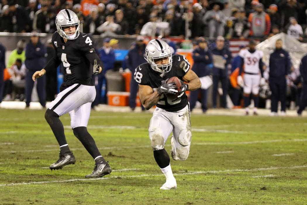 Oakland Raiders quarterback Derek Carr (4) hands off the football to running back Doug Martin (28) during the first half of an NFL game against the Denver Broncos in Oakland, Calif., Monday, Dec. ...