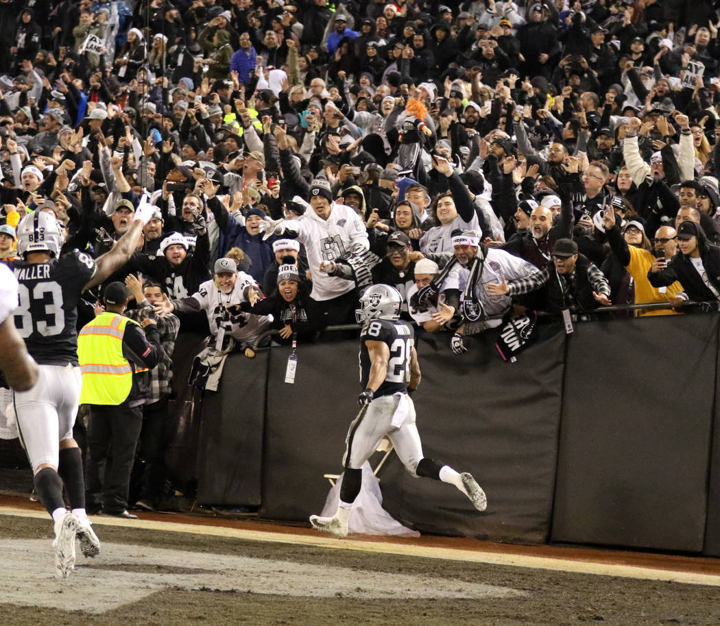 Oakland Raiders running back Doug Martin (28) scores a touchdown against the Denver Broncos and celebrates with fans during the first half of an NFL game in Oakland, Calif., Monday, Dec. 24, 2018. ...