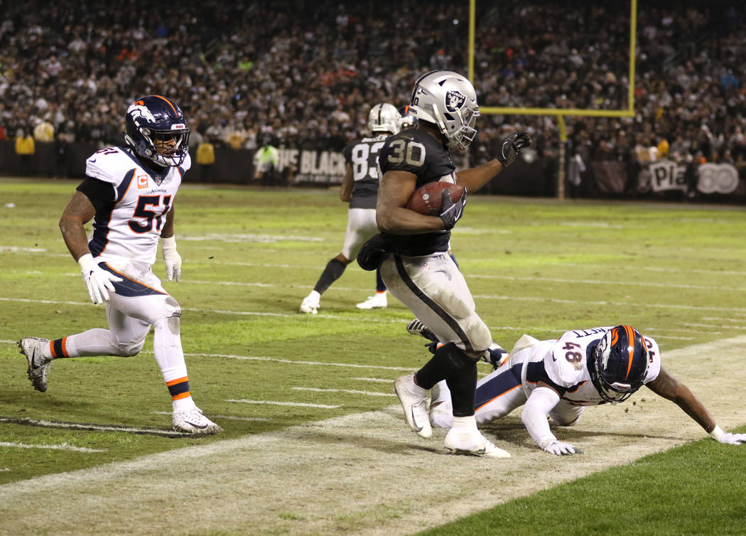 Oakland Raiders running back Jalen Richard (30) runs out of bounds as Denver Broncos linebacker Shaquil Barrett (48) and inside linebacker Todd Davis (51) close in during the first half of an NFL ...