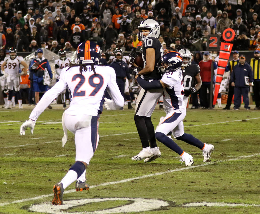 Oakland Raiders wide receiver Seth Roberts (10) makes a catch as Denver Broncos free safety Justin Simmons (31) tackles him during the first half of an NFL game in Oakland, Calif., Monday, Dec. 24 ...