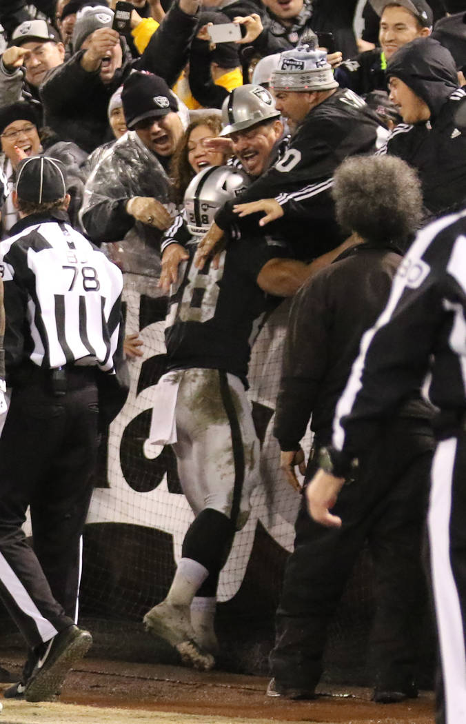 Oakland Raiders running back Doug Martin (28) scores a touchdown against the Denver Broncos and celebrates with fans during the first half of an NFL game in Oakland, Calif., Monday, Dec. 24, 2018. ...