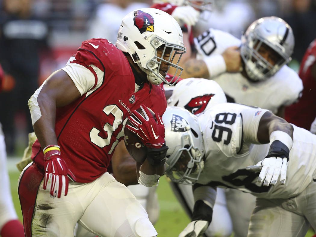 Arizona Cardinals running back David Johnson (31) runs as Oakland Raiders defensive end Frostee Rucker (98) makes the hit during the first half of an NFL football game, Sunday, Nov. 18, 2018, in G ...