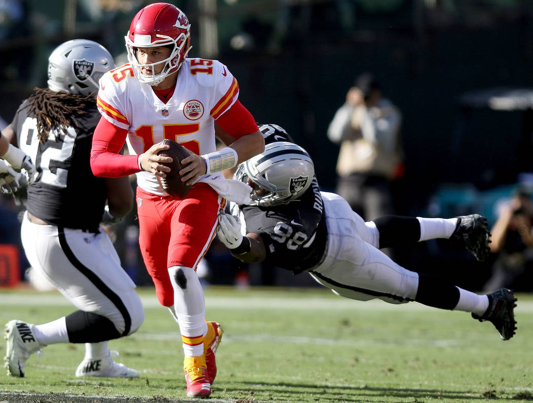 Kansas City Chiefs quarterback Patrick Mahomes (15) sheds tackle by Oakland Raiders defensive end Frostee Rucker (98) as Raiders defensive tackle P.J. Hall (92) and Chiefs offensive tackle Mitchel ...